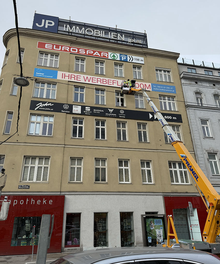 Montage einer Fassadenwerbung mit einer Hebebühne